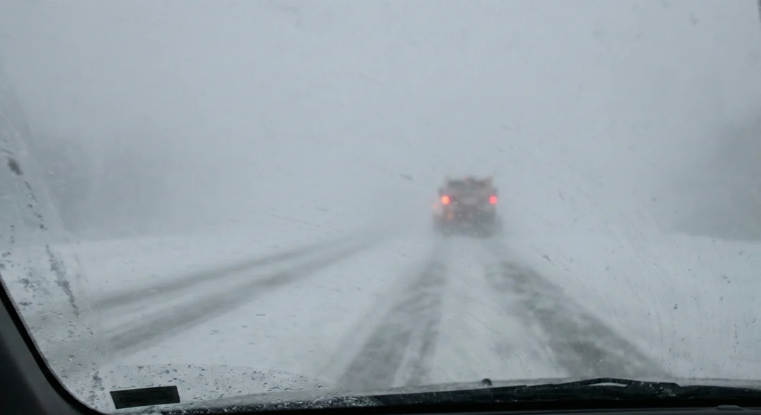 Snow-covered highway in a winter whiteout with faint taillights ahead, representing how AI search visibility narrows results to trusted sources